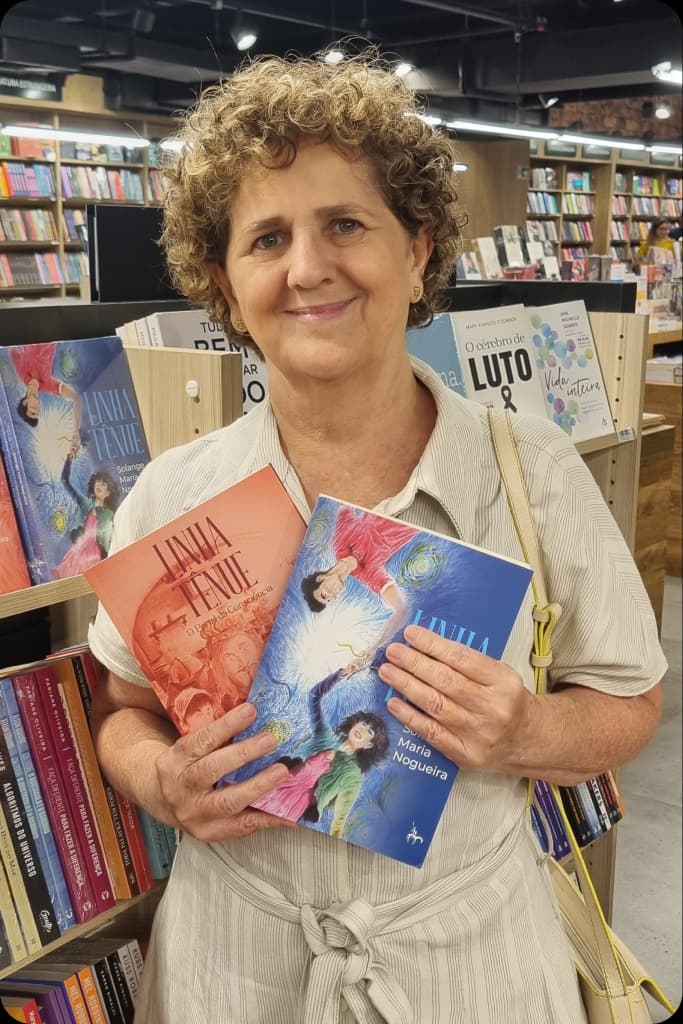 Solange Maria Nogueira segurando dois exemplares do romance Linha Tênue